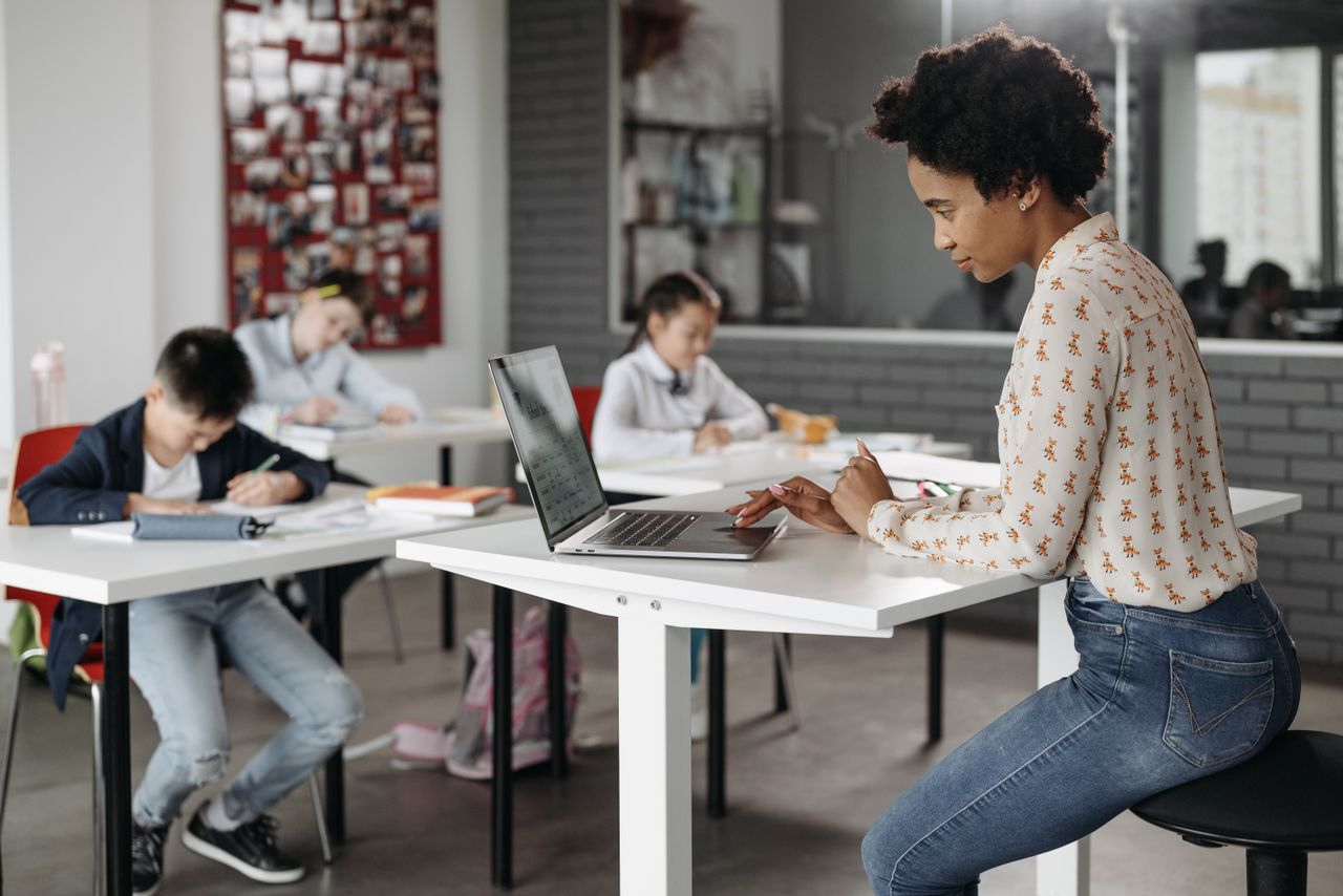 Services Focused teacher with students working at desks in an indoor classroom environment.